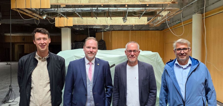Bauamtsleiter Eppo Haas, Bürgermeister Christian Litzinger, hkr-Architekt Claus Rollmann und Projektleiter im Bauamt Peter Hartmannsberger stehen gemeinsam in der Stadthalle Gelnhausen.  