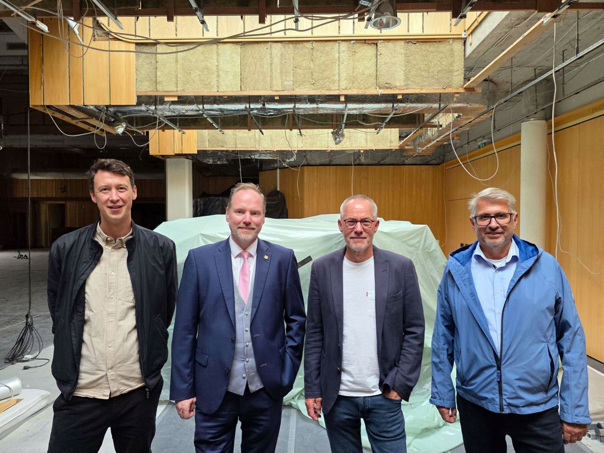 Bauamtsleiter Eppo Haas, Bürgermeister Christian Litzinger, hkr-Architekt Claus Rollmann und Projektleiter im Bauamt Peter Hartmannsberger stehen gemeinsam in der Stadthalle Gelnhausen.  