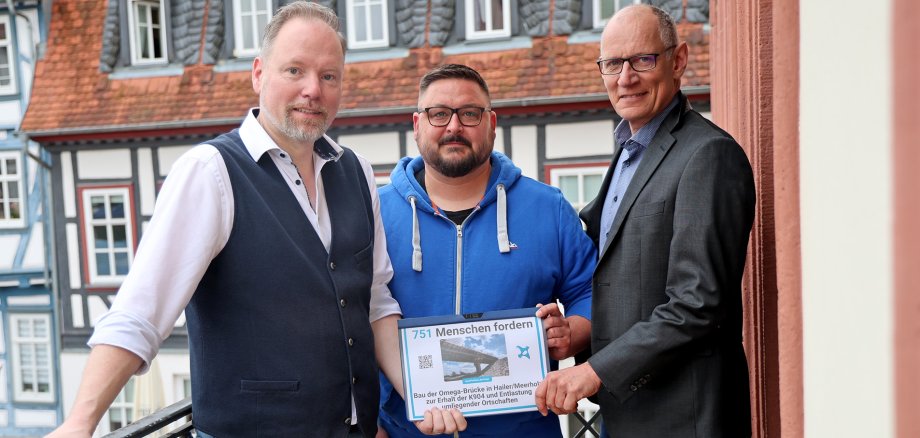 Bürgermeister Christian Litzinger, Hauptamtsleiter Stefan Bechtold und Alexander Magiera stehen gemeinsam auf dem Rathausbalkon mit der Unterschriftenliste. 