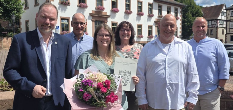 Bürgermeister Christian Litzinger, Ausbildungsabsolventin Lea Mohn und Mitarbeiterinnen und Mitarbeiter des Rathauses stehen auf dem Obermarkt vor der alten Bürgerschule. 