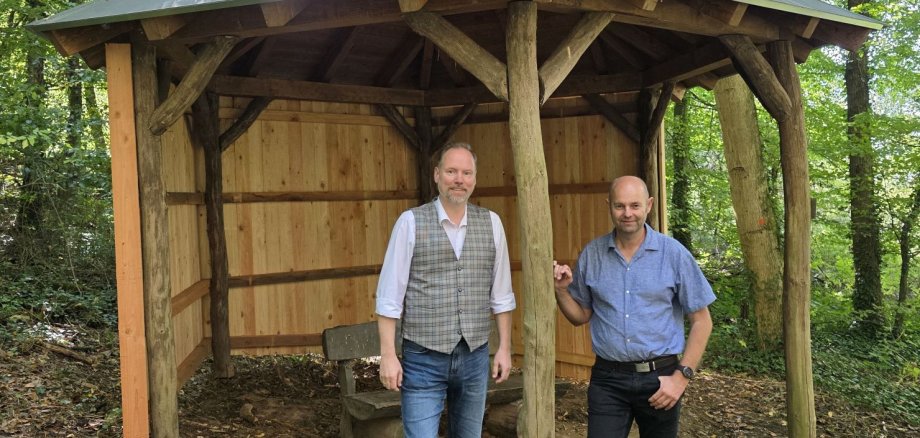 Wanderunterstände im Wald von Hailer und Meerholz saniert Bürgermeister Christian Litzinger und Bauamtsmitarbeiter Thorsten Amend stehen zusammen vor der sanierten Wanderschutzhütte in Meerholz.
