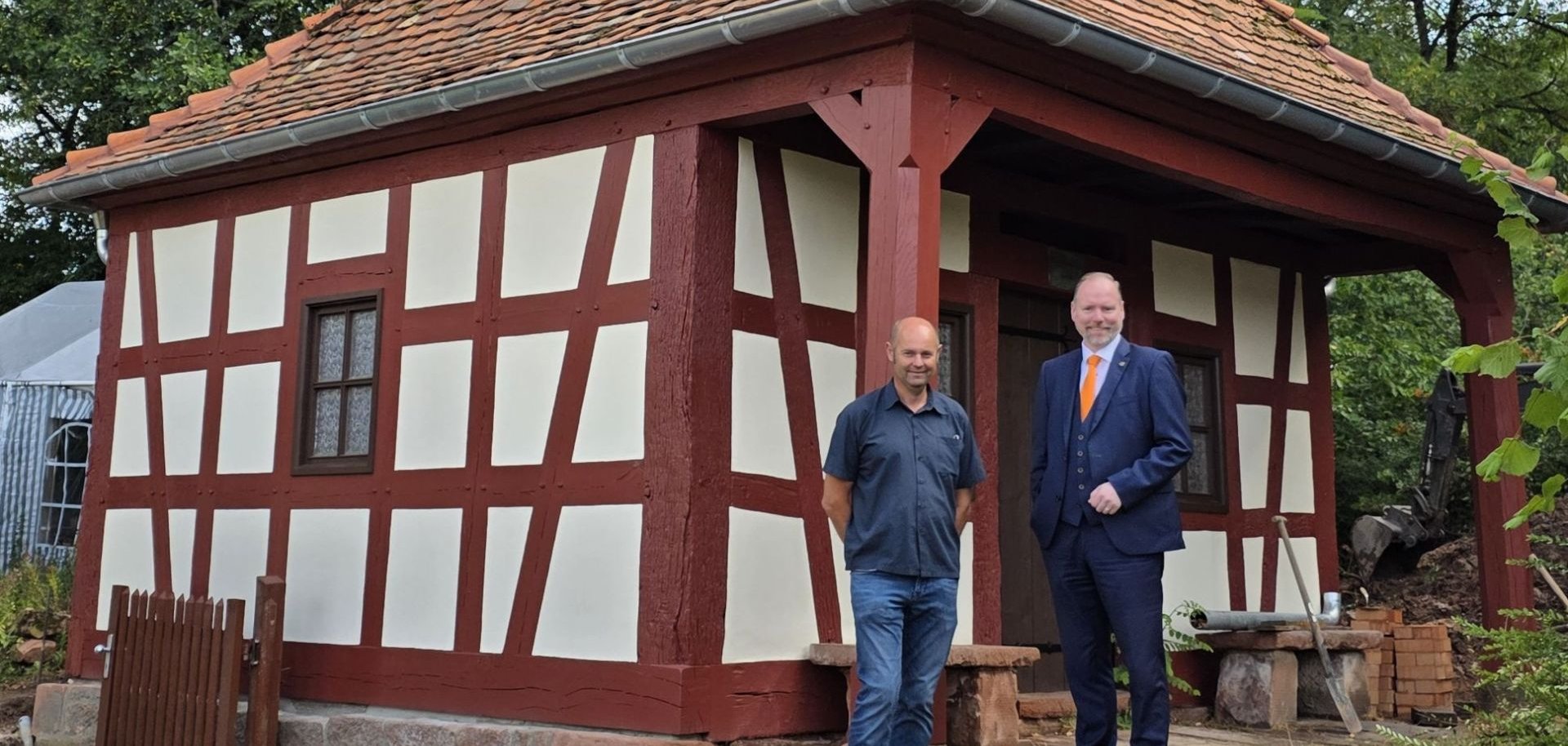Bürgermeister Christian Litzinger und Bauamtsmitarbeiter Thorsten Amend stehen vor dem Wingertshäuschen in Meerholz.