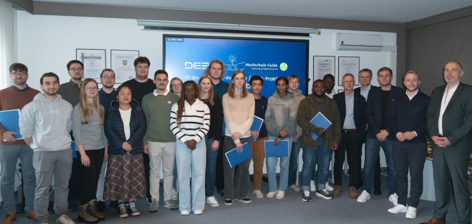 Eine Gruppe Menschen steht in einem Seminarraum. 