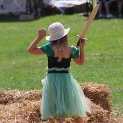 Ein Mädchen mit Hut und Holzschwert. 