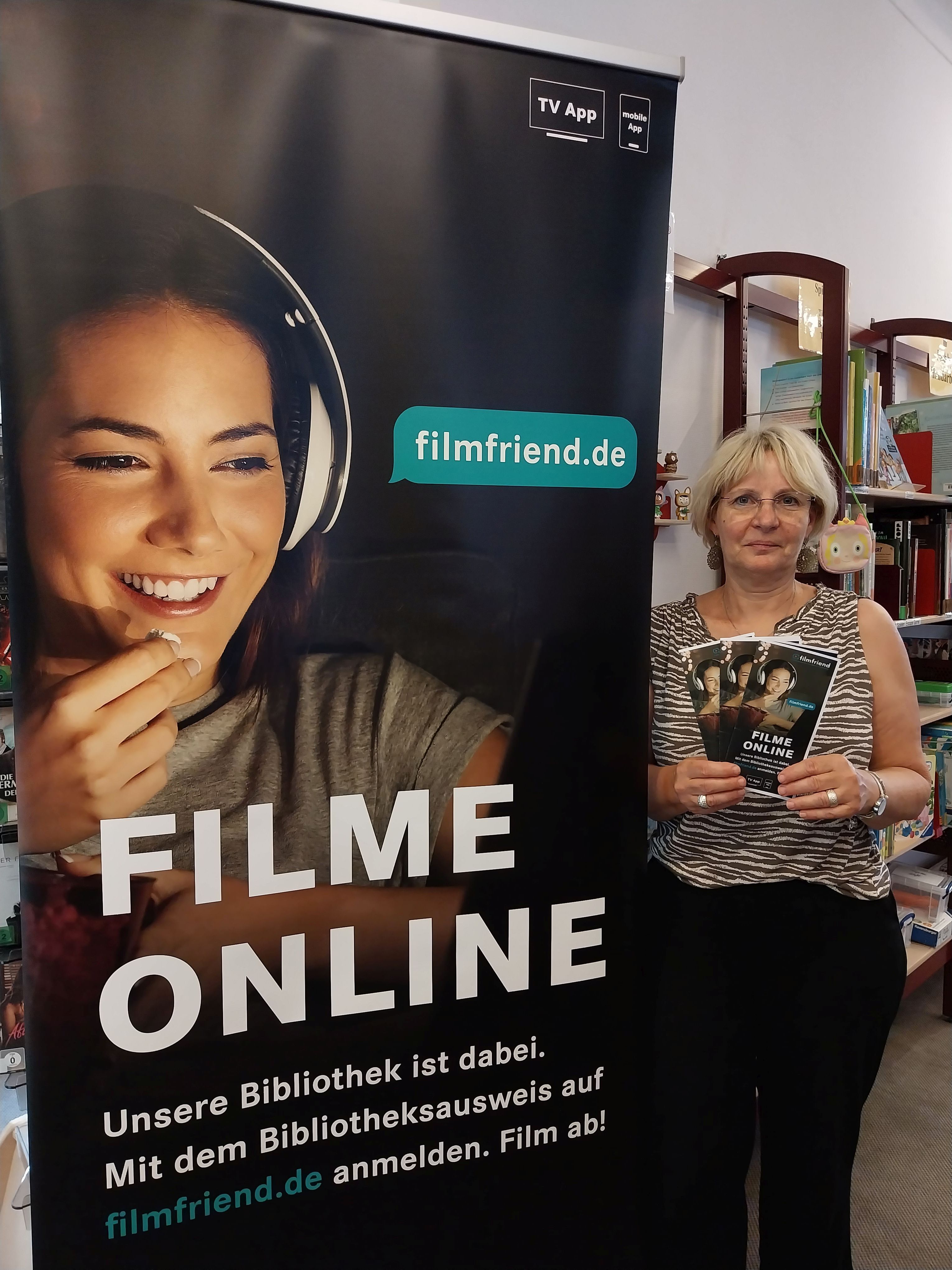 Büchereileiterin Beck vor dem Werbeplakat für den Online-Filmdienst.