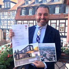 Bürgermeister Daniel Christian Glöckner hält das Bewilligungsschreiben des Hessischen Innenministers für die Förderung einer lebendigen Innenstadt Gelnhausens in die Kamera.