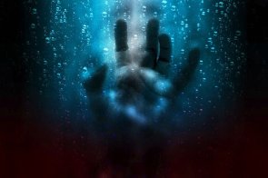 Symbolbild Angst Zu sehen ist die Silhouette einer offenen Hand die unterwasser nach Luft sucht. In der Mitte ist ein blaues Licht, das die Hand erleuchtet.