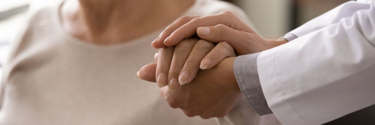 Ein Arzt hält die Hand einer Patientin.