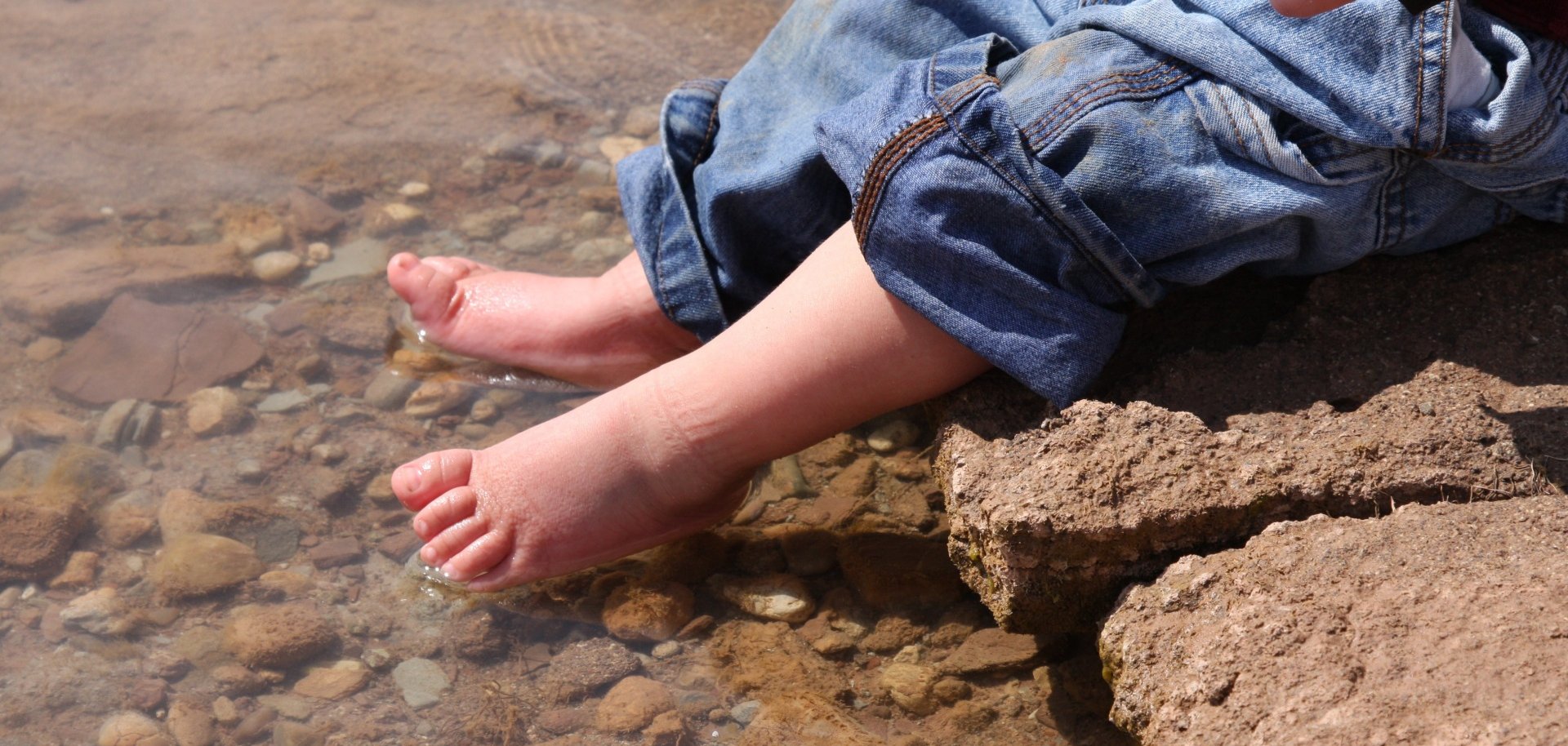 Ein Kleinkind kühlt seine Füßchen im Wasser. 