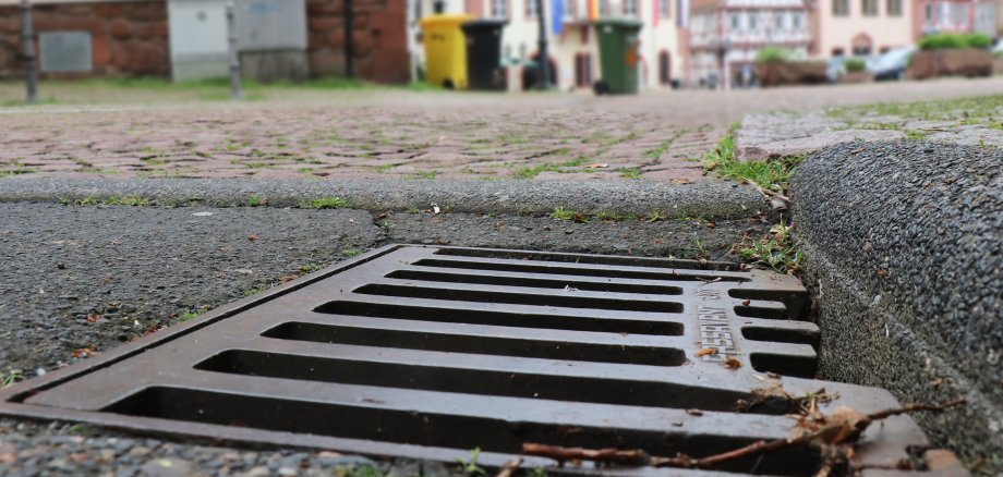 Nahaufnahme eines Straßenablaufs, im Hintergrund Obermarkt und Rathaus.