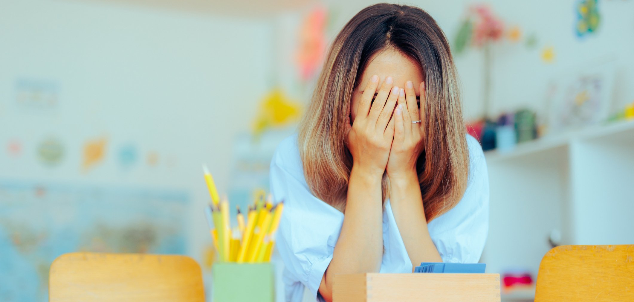 Eine überforderte Erzieherin schlägt die Hände vors Gesicht.