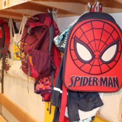 Symbolbild. Zu sehen ist der Ausschnitt einer typischen Kindertagesstätten-Garderobe, im Vordergrund dominiert ein Rucksack mit Spiderman-Motiv. 